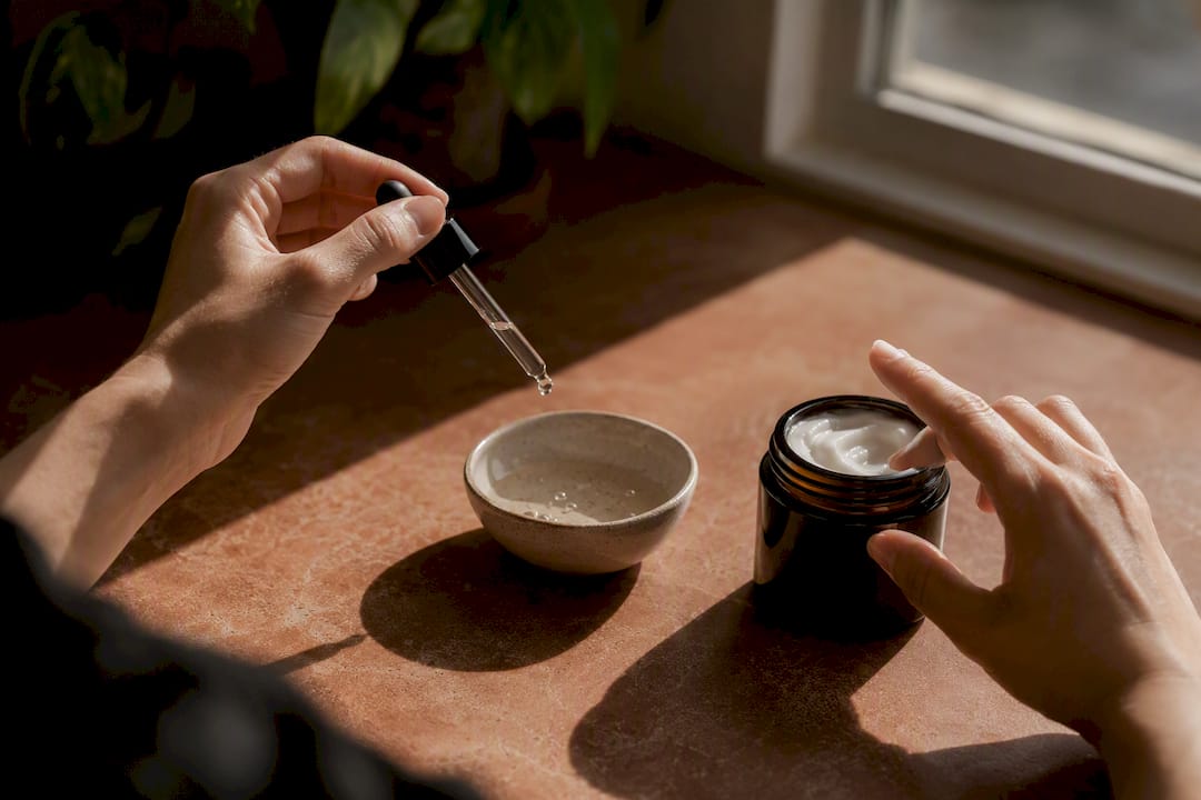 Hands applying serum and moisturizer on dark counter