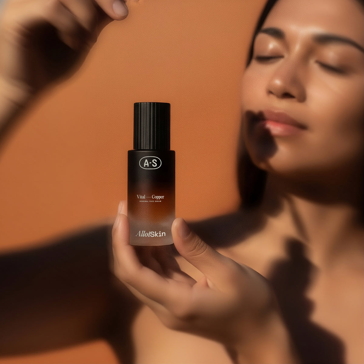 Person holding an Alloi Skin bottle gainst an orange background