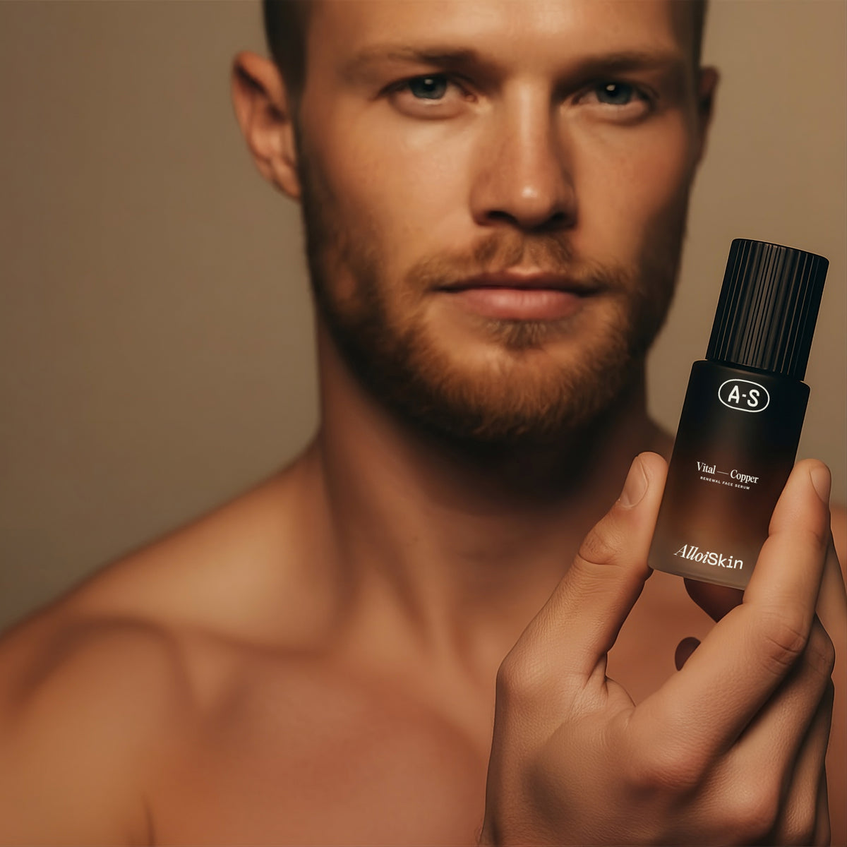 Man holding a bottle of Alloi Skin product against a neutral background